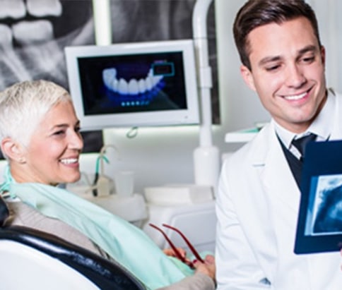 The dentist is discussing the x-ray results with the patient during a service.