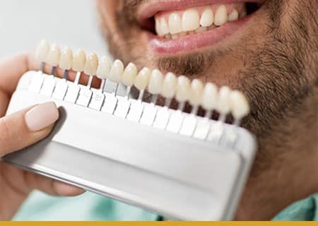 A man is holding a toothbrush in his hand for cosmetic dentistry in Hamilton.