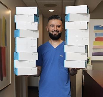 A man holding a stack of boxes in the office while his team works on SEO strategies.
