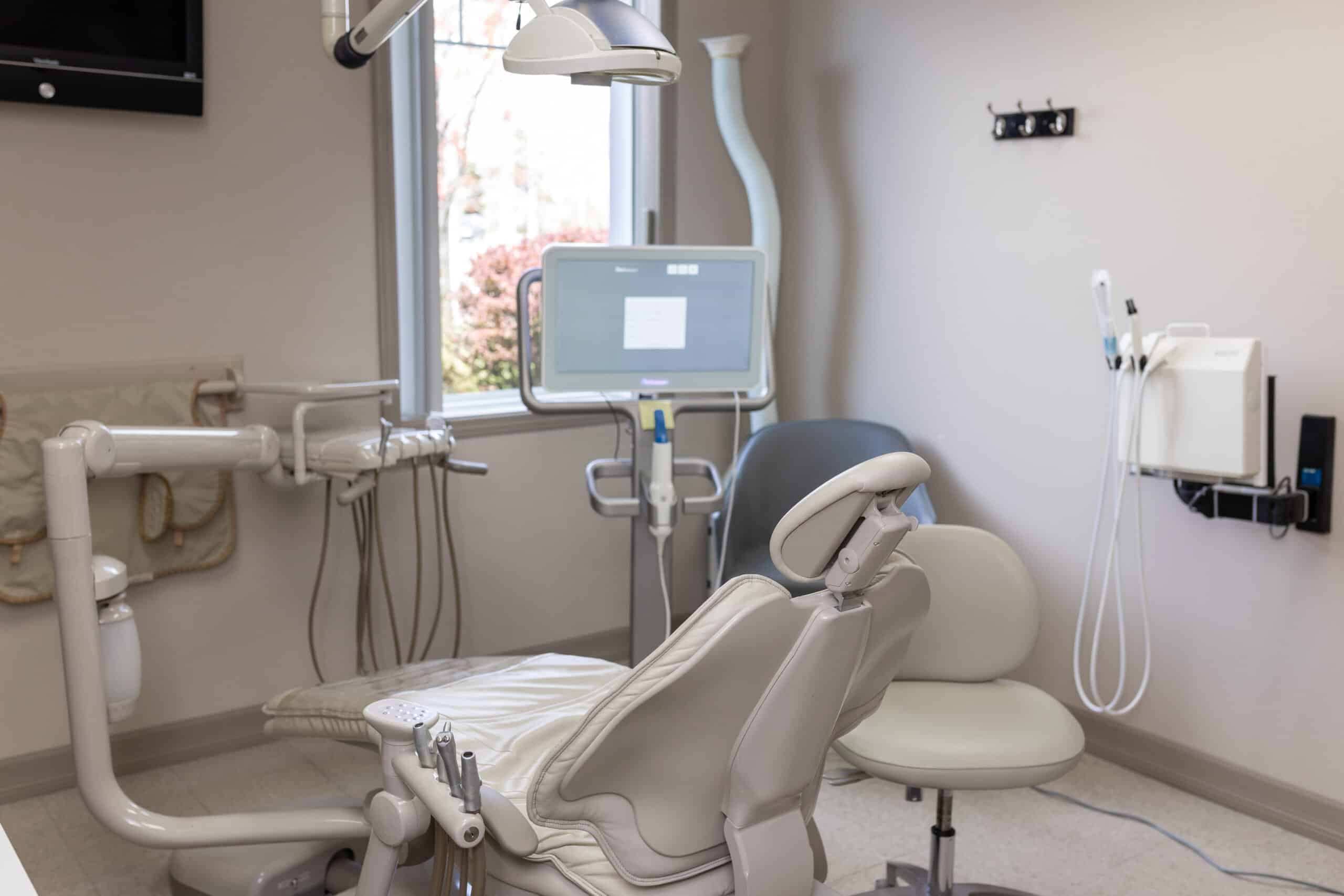 A dental room in Hamilton with a chair and monitor for cosmetic dentistry.