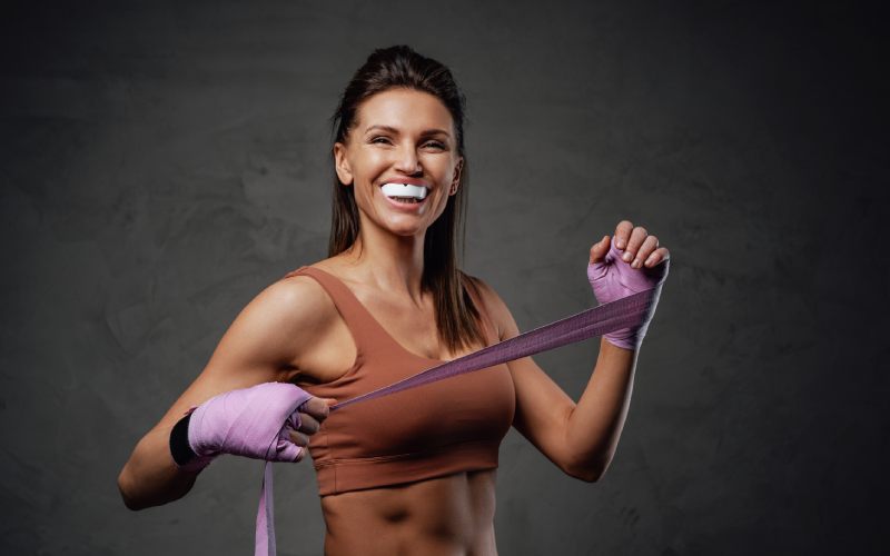 smiling sportswoman poses-dark background bandages